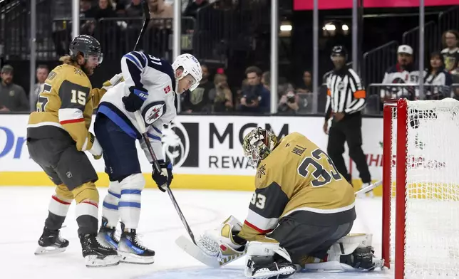 Winnipeg Jets center Cole Perfetti (91) scores against Vegas Golden Knights defenseman Noah Hanifin (15) and goaltender Adin Hill (33) during the first period of an NHL hockey game Friday, Nov. 29, 2024, in Las Vegas. (AP Photo/Ian Maule)