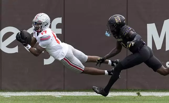 Ohio State wide receiver Carnell Tate State makes a diving touchdown reception as Northwestern defensive back Josh Fussell defends during the first half of an NCAA college football game at Wrigley Field, Saturday, Nov. 16, 2024, in Chicago. (AP Photo/Charles Rex Arbogast)