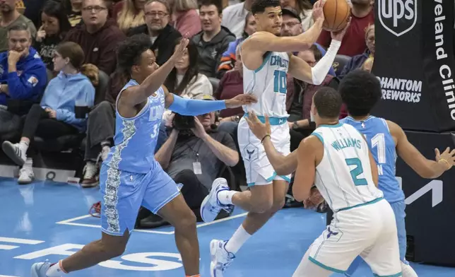 Charlotte Hornets' Josh Green (10) looks to pass the ball as Cleveland Cavaliers' Isaac Okoro, left, defends while Hornets' Grant Williams (2) and Cavaliers' Jarrett Allen, right, watch during the first half of an NBA basketball game in Cleveland, Sunday, Nov 17, 2024. (AP Photo/Phil Long)