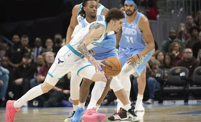 Charlotte Hornets' LaMelo Ball, front, drives past Cleveland Cavaliers' Darius Garland, center, and Jarrett Allen (31) during the first half of an NBA basketball game in Cleveland, Sunday, Nov 17, 2024. (AP Photo/Phil Long)