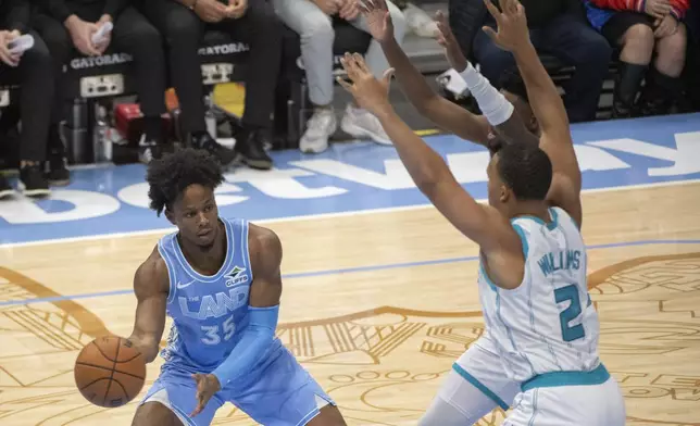 Cleveland Cavaliers' Isaac Okoro (35) passes around Charlotte Hornets' Grant Williams (2) during the first half of an NBA basketball game in Cleveland, Sunday, Nov 17, 2024. (AP Photo/Phil Long)