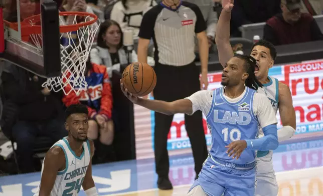 Cleveland Cavaliers' Darius Garland (10) lays in a shot as Charlotte Hornets' Josh Green, right, defends and Hornets' Brandon Miller (24) watches during the first half of an NBA basketball game in Cleveland, Sunday, Nov 17, 2024. (AP Photo/Phil Long)