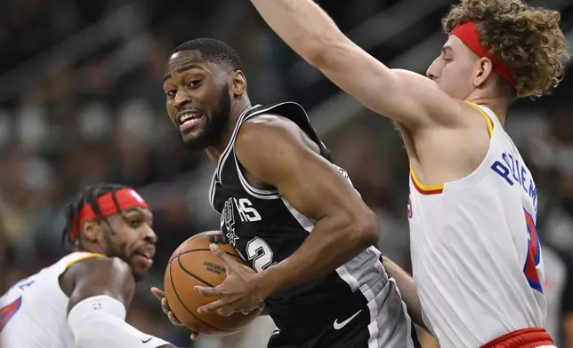 San Antonio Spurs guard Malaki Branham, center, tangles with Golden State Warriors' Brandin Podziemski, right, and Buddy Hield, left, during the first half of an NBA basketball game, Saturday, Nov. 23, 2024, in San Antonio. (AP Photo/Darren Abate)