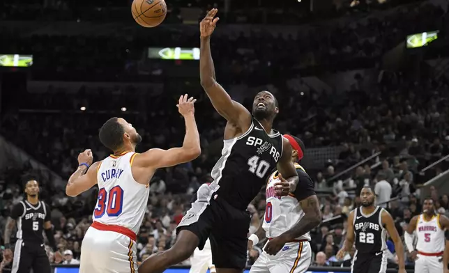 San Antonio Spurs' Harrison Barnes (40) tangles with Golden State Warriors' Stephen Curry (30) and Gary Payton II (0) during the first half of an NBA basketball game, Saturday, Nov. 23, 2024, in San Antonio. (AP Photo/Darren Abate)