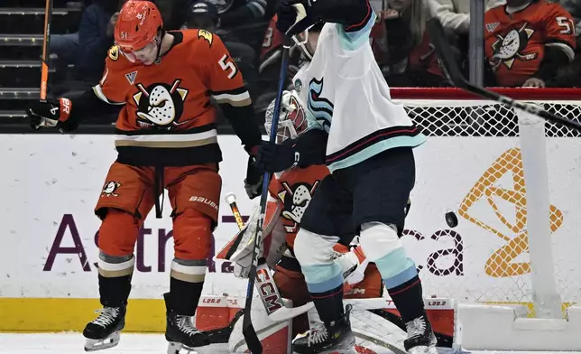 Seattle Kraken center Shane Wright, right, deflects the puck to score against Anaheim Ducks defenseman Olen Zellweger, left, and goaltender Lukas Dostal, center, during the first period of an NHL hockey game in Anaheim, Calif., Monday, Nov. 25, 2024. (AP Photo/Alex Gallardo)