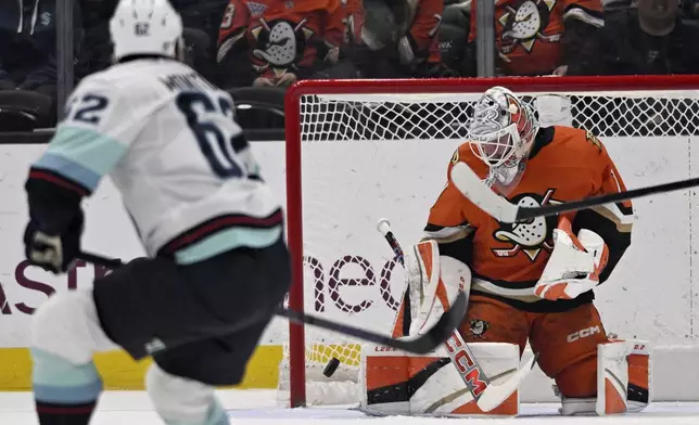 Anaheim Ducks goaltender Lukas Dostal (1) deflects the puck with Seattle Kraken defenseman Brandon Montour (62) watching during the first period of an NHL hockey game in Anaheim, Calif., Monday, Nov. 25, 2024. (AP Photo/Alex Gallardo)