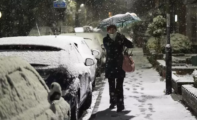 A person walks down a street during snowfall in Warwick, England, Tuesday, Nov. 19, 2024. (Jacob King/PA Wire/PA via AP)