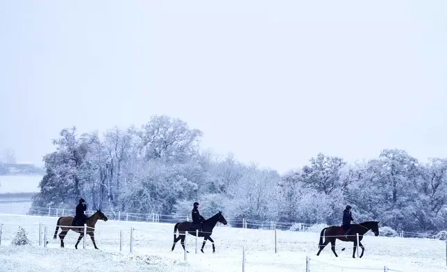 People ride horses after a snowfall at Sam Drinkwater's Granary Stables, Strensham, England, Tuesday, Nov. 19, 2024. (David Davies/PA via AP)