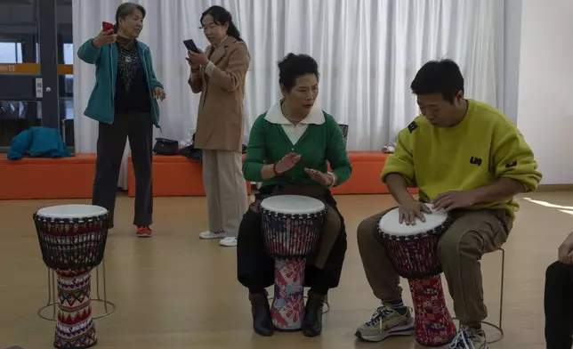 Cai Guixia, 60, second from right, learns African drumming from an instructor at the University for the Elderly in Beijing, Oct. 23, 2024. (AP Photo/Ng Han Guan)