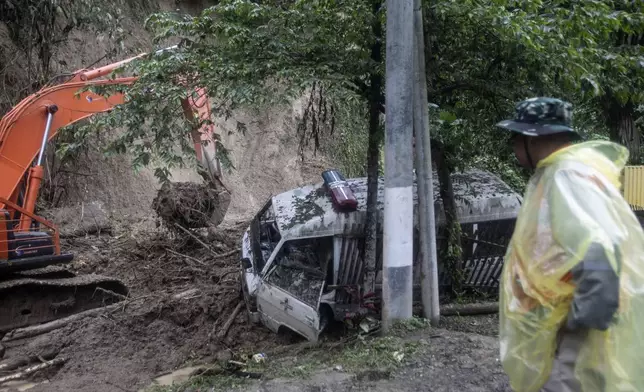 A rescuer watches heavy machine clear up mud after a landslide hit a road killing a number of people in Sibolangit, North Sumatra, Indonesia, Thursday, Nov. 28, 2024. (AP Photo/Binsar Bakkara)