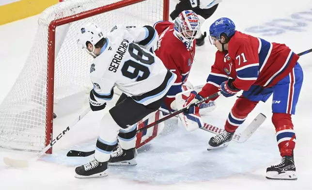 Utah Hockey Club's Mikhail Sergachev (98) scores against Montreal Canadiens goaltender Sam Montembeault as Canadiens' Jake Evans (71) defends during overtime NHL hockey action in Montreal, Tuesday, Nov. 26, 2024. (Graham Hughes/The Canadian Press via AP)