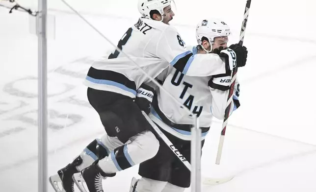 Utah Hockey Club's Mikhail Sergachev, right, celebrates with teammate Nick Schmaltz (8) after scoring against the Montreal Canadiens during overtime in an NHL hockey game in Montreal, Tuesday, Nov, 26, 2024. (Graham Hughes/The Canadian Press via AP)