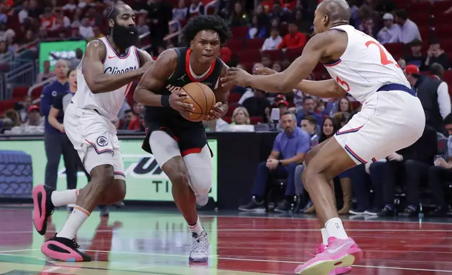 Houston Rockets forward Amen Thompson, center, drives between Los Angeles Clippers guard James Harden (1) and forward Kai Jones (23) during the first half of an Emirates NBA Cup basketball game Friday, Nov. 15, 2024, in Houston. (AP Photo/Michael Wyke)