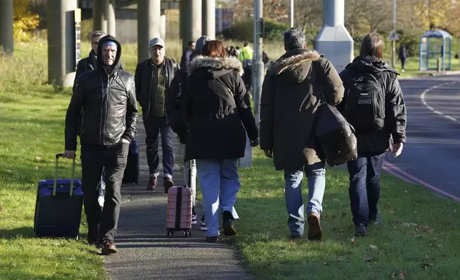 Passengers walk at Gatwick airport, where flights have been cancelled and delayed after a "suspected prohibited item" was found in luggage, in Crawley, England, Friday Nov. 22, 2024. (Gareth Fuller/via AP)