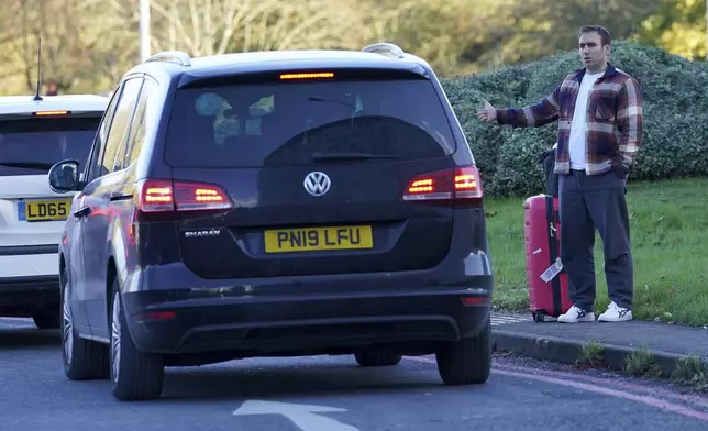 A passenger hitchhikes outside Gatwick airport, where flights have been cancelled and delayed after a "suspected prohibited item" was found in luggage, near Crawley, England, Friday Nov. 22, 2024. (Gareth Fuller/PA via AP)