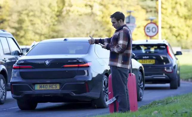 A passenger hitchhikes at Gatwick airport, where flights have been cancelled and delayed after a "suspected prohibited item" was found in luggage, near Crawley, England, Friday Nov. 22, 2024. (Gareth Fuller/PA via AP)