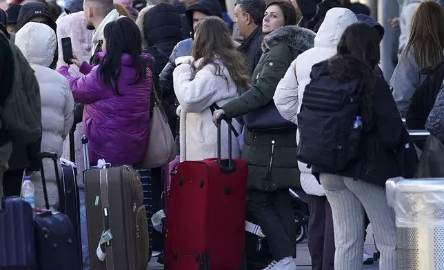 Passengers stand outside Gatwick airport, where flights have been cancelled and delayed after a "suspected prohibited item" was found in luggage, in Crawley, England, Friday Nov. 22, 2024. (Gareth Fuller/PA via AP)