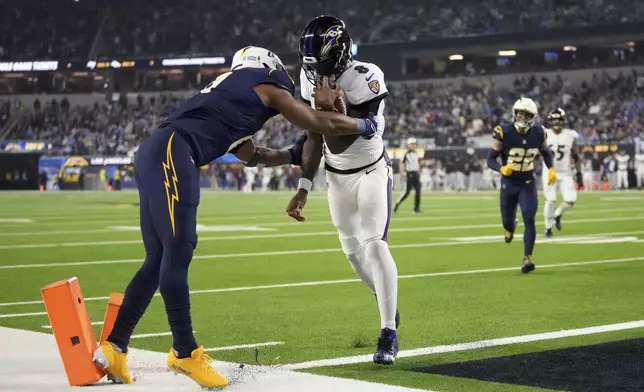 Baltimore Ravens quarterback Lamar Jackson (8) scores a rushing touchdown as Los Angeles Chargers linebacker Daiyan Henley attempts a tackle during the first half of an NFL football game Monday, Nov. 25, 2024, in Inglewood, Calif. (AP Photo/Eric Thayer)