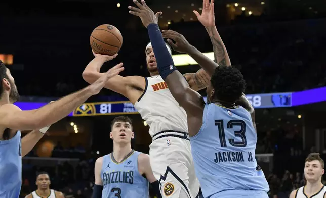 Denver Nuggets forward Michael Porter Jr. looks to pass between Memphis Grizzlies forwards Jake LaRavia (3), and Jaren Jackson Jr. (13) in the second half of an Emirates NBA Cup basketball game Tuesday, Nov. 19, 2024, in Memphis, Tenn. (AP Photo/Brandon Dill)