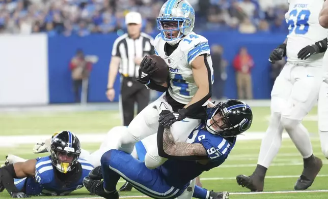 Detroit Lions wide receiver Amon-Ra St. Brown (14) is tackled by Indianapolis Colts defensive end Laiatu Latu (97) during the second half of an NFL football game, Sunday, Nov. 24, 2024, in Indianapolis. (AP Photo/AJ Mast)