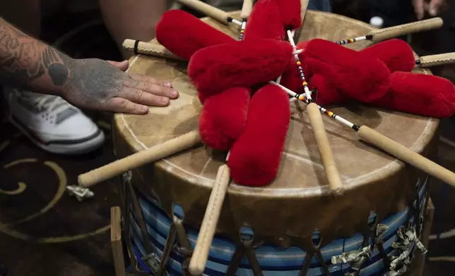 Taylor Hawk, a member of the Warrior Society drum group, touches the drum after playing during a powwow at Chinook Winds Casino Resort, Saturday, Nov. 16, 2024, in Lincoln City, Ore. (AP Photo/Jenny Kane)