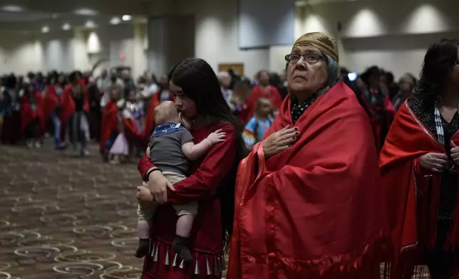 Confederated Tribes of Siletz Indians member Ramona Hudson, of Aumsville, Ore., right, looks up as her cousin Aurora Chulik-Ruff, 12, holds her five-month-old brother Bear Chulik-Moore, as they walk during a dance dedicated to missing and murdered indigenous women during a powwow at Chinook Winds Casino Resort, Saturday, Nov. 16, 2024, in Lincoln City, Ore. (AP Photo/Jenny Kane)