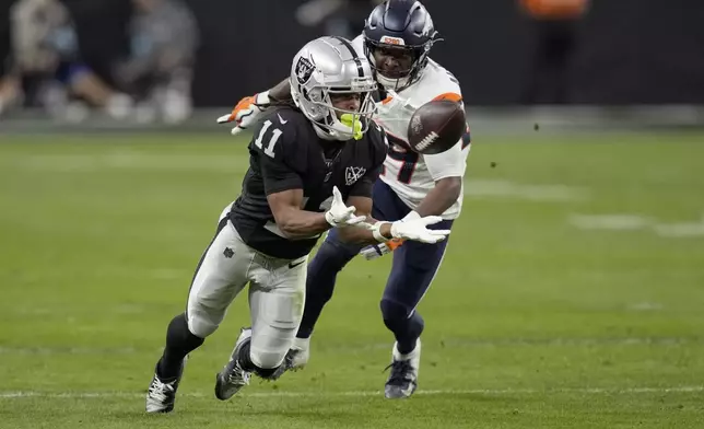 Las Vegas Raiders wide receiver Tre Tucker (11) makes a catch as Denver Broncos cornerback Ja'Quan McMillian defends during the second half of an NFL football game, Sunday, Nov. 24, 2024, in Las Vegas. (AP Photo/John Locher)