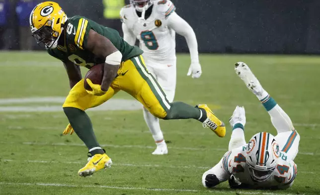 Green Bay Packers running back Josh Jacobs (8) breaks a tackle by Miami Dolphins linebacker Chop Robinson (44) during the second half of an NFL football game Thursday, Nov. 28, 2024, in Green Bay, Wis. (AP Photo/Mike Roemer)