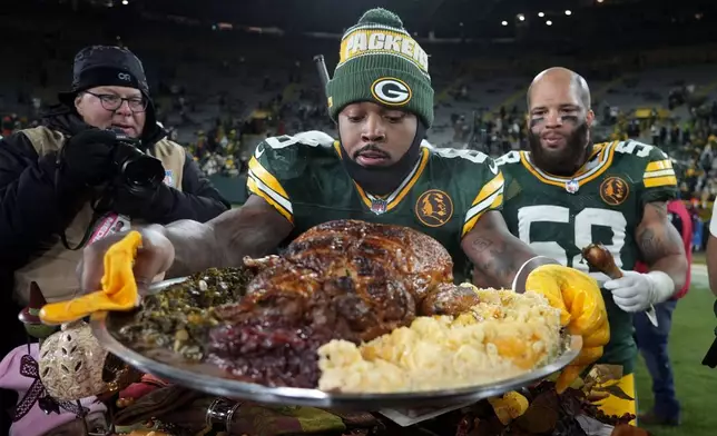 Green Bay Packers running back Josh Jacobs (8) holds a plate of turkey after an NFL football game against the Miami Dolphins Thursday, Nov. 28, 2024, in Green Bay, Wis. (AP Photo/Morry Gash)