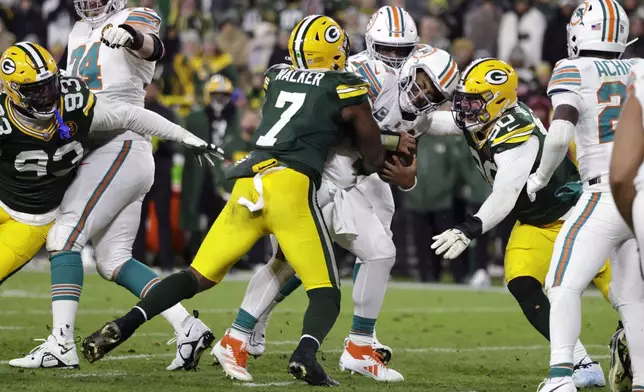 Miami Dolphins quarterback Tua Tagovailoa is sacked by Green Bay Packers linebacker Quay Walker (7) and defensive end Lukas Van Ness (90) during the second half of an NFL football game Thursday, Nov. 28, 2024, in Green Bay, Wis. (AP Photo/Matt Ludtke)