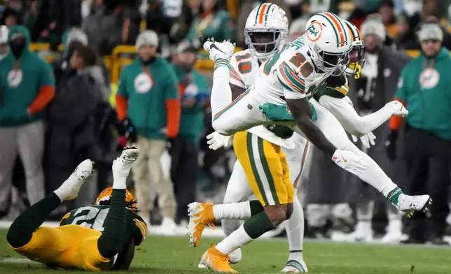 Miami Dolphins running back De'Von Achane (28) leaps over Green Bay Packers safety Javon Bullard, left, during the first half of an NFL football game Thursday, Nov. 28, 2024, in Green Bay, Wis. (AP Photo/Morry Gash)