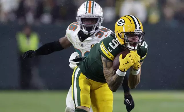 Green Bay Packers wide receiver Christian Watson (9) catches a pass ahead of Miami Dolphins cornerback Storm Duck (36) during the second half of an NFL football game Thursday, Nov. 28, 2024, in Green Bay, Wis. (AP Photo/Matt Ludtke)