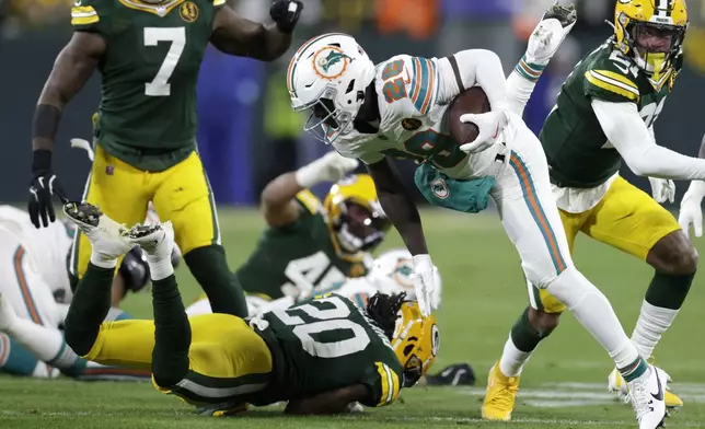 Miami Dolphins running back De'Von Achane (28) leaps over Green Bay Packers safety Javon Bullard (20) during the first half of an NFL football game Thursday, Nov. 28, 2024, in Green Bay, Wis. (AP Photo/Matt Ludtke)