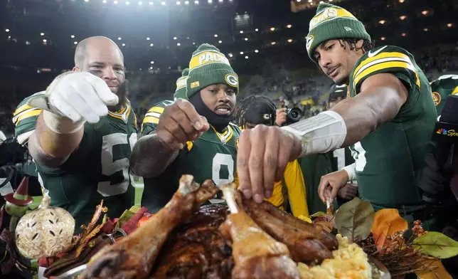 Green Bay Packers linebacker Isaiah McDuffie, from left, running back Josh Jacobs and quarterback Jordan Love eat turkey legs after an NFL football game against the Miami Dolphins Thursday, Nov. 28, 2024, in Green Bay, Wis. (AP Photo/Morry Gash)