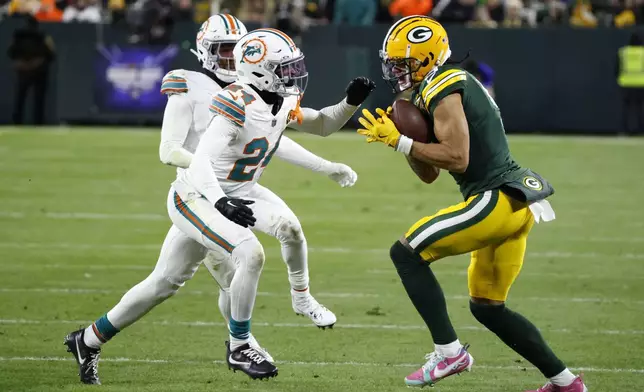 Green Bay Packers wide receiver Christian Watson runs from Miami Dolphins cornerback Cam Smith, left, after catching a pass during the first half of an NFL football game Thursday, Nov. 28, 2024, in Green Bay, Wis. (AP Photo/Mike Roemer)