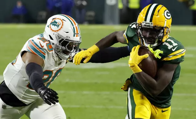 Green Bay Packers wide receiver Jayden Reed (11) runs from Miami Dolphins linebacker Jordyn Brooks (20) during a 12-yard touchdown reception in the first half of an NFL football game Thursday, Nov. 28, 2024, in Green Bay, Wis. (AP Photo/Mike Roemer)