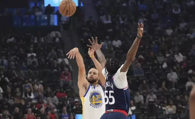 Golden State Warriors guard Stephen Curry, left shoots as Los Angeles Clippers forward Derrick Jones Jr. defends ,during the first half of an NBA basketball game, Monday, Nov. 18, 2024, in Inglewood, Calif. (AP Photo/Mark J. Terrill)