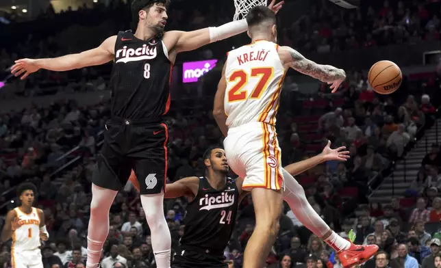 Atlanta Hawks guard Vit Krejci, right, passes the ball on Portland Trail Blazers forward Deni Avdija, left, as forward Kris Murray, center, defends during the first half of an NBA basketball game in Portland, Ore., Sunday, Nov. 17, 2024. (AP Photo/Steve Dykes)