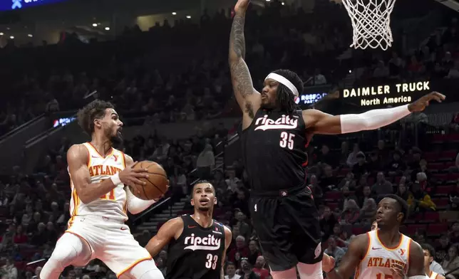 Atlanta Hawks guard Trae Young, left, looks to pass the ball against Portland Trail Blazers center Robert Williams III (35) as Trail Blazers forward Toumani Camara (33) defends during the first half of an NBA basketball game in Portland, Ore., Sunday, Nov. 17, 2024. (AP Photo/Steve Dykes)