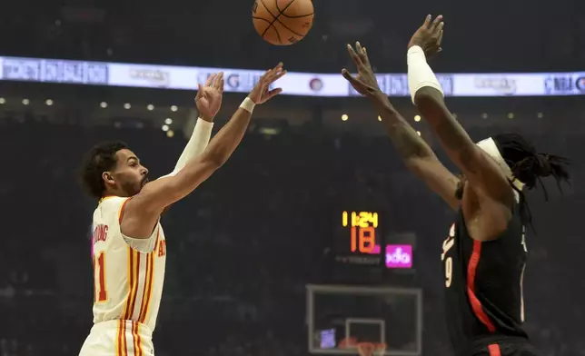 Atlanta Hawks guard Trae Young, left, shoots the ball over Portland Trail Blazers forward Jerami Grant, right, during the first half of an NBA basketball game in Portland, Ore., Sunday, Nov. 17, 2024. (AP Photo/Steve Dykes)