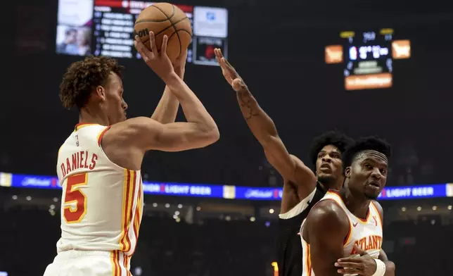 Atlanta Hawks guard Dyson Daniels, left, looks to shoot over Portland Trail Blazers guard Scoot Henderson, center, as Hawks center Clint Capela, right, defends during the first half of an NBA basketball game in Portland, Ore., Sunday, Nov. 17, 2024. (AP Photo/Steve Dykes)