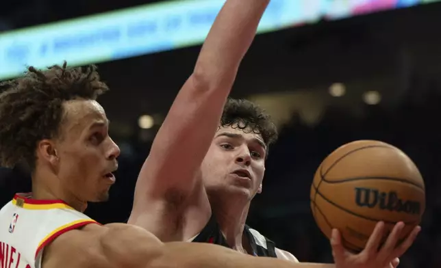 Atlanta Hawks guard Dyson Daniels, left, looks to shoot as Portland Trail Blazers center Donovan Clingan (23) defends during the first half of an NBA basketball game Sunday, Nov. 17, 2024, in Portland, Ore. (AP Photo/Jenny Kane)