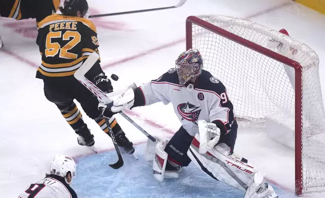 Columbus Blue Jackets goaltender Elvis Merzlikins (90) makes a save against Boston Bruins defenseman Andrew Peeke (52) during the first period of an NHL hockey game, Monday, Nov. 18, 2024, in Boston. (AP Photo/Charles Krupa)