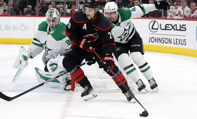 Carolina Hurricanes' Sebastian Aho (20) controls the puck in front of Dallas Stars goaltender Jake Oettinger (29) and Miro Heiskanen (4) during the second period of an NHL hockey game in Raleigh, N.C., Monday, Nov. 25, 2024. (AP Photo/Karl B DeBlaker)