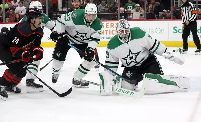 Carolina Hurricanes' Seth Jarvis (24) chases the puck past Dallas Stars' Esa Lindell (23) and goaltender Jake Oettinger (29) during the second period of an NHL hockey game in Raleigh, N.C., Monday, Nov. 25, 2024. (AP Photo/Karl B DeBlaker)