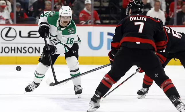 Dallas Stars' Sam Steel (18) clears the puck past Carolina Hurricanes' Dmitry Orlov (7) during the first period of an NHL hockey game in Raleigh, N.C., Monday, Nov. 25, 2024. (AP Photo/Karl B DeBlaker)