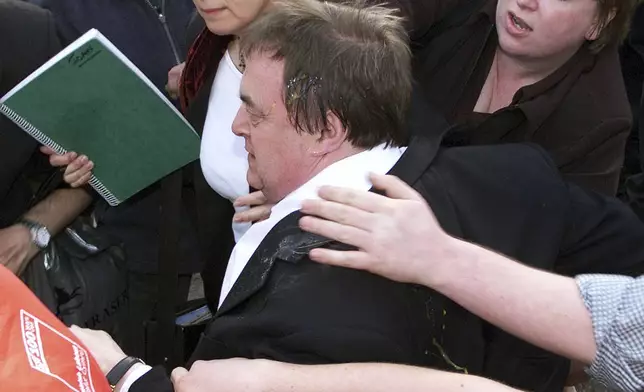 FILE -Britain's deputy prime minister John Prescott, covered in egg and ruffed up, being separated from his attacker, in the North Wales seaside resort of Rhyl where he was to address a Labour Party rally, May, 16, 2001.(David Kendall/PA via AP, File)