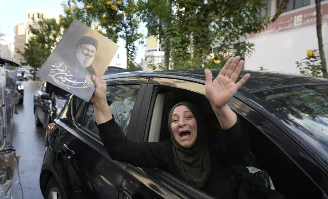 A woman carries a picture of slain Hezbollah leader Hassan Nasrallah as she returns to Dahiyeh, in Beirut, Lebanon, following a ceasefire between Israel and Hezbollah, Wednesday, Nov. 27, 2024. (AP Photo/Bilal Hussein)