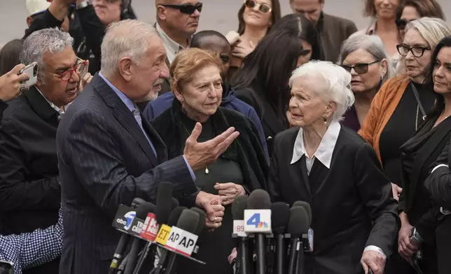 Holding the hand of Marta Cano, the sister of Jose Menendez, attorney Mark Geragos, left, talks to Joan VanderMolen, Erik and Lyle Menendez's aunt, during a news conference after a hearing in Los Angeles, Monday, Nov. 25, 2024. (AP Photo/Jae C. Hong)