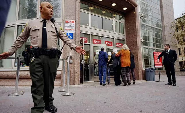 A Los Angeles County sheriff's deputy maintains a perimeter around the Van Nuys courthouse for the hearing for Erik and Lyle Menendez in Los Angeles, Monday, Nov. 25, 2024. (AP Photo/Damian Dovarganes)